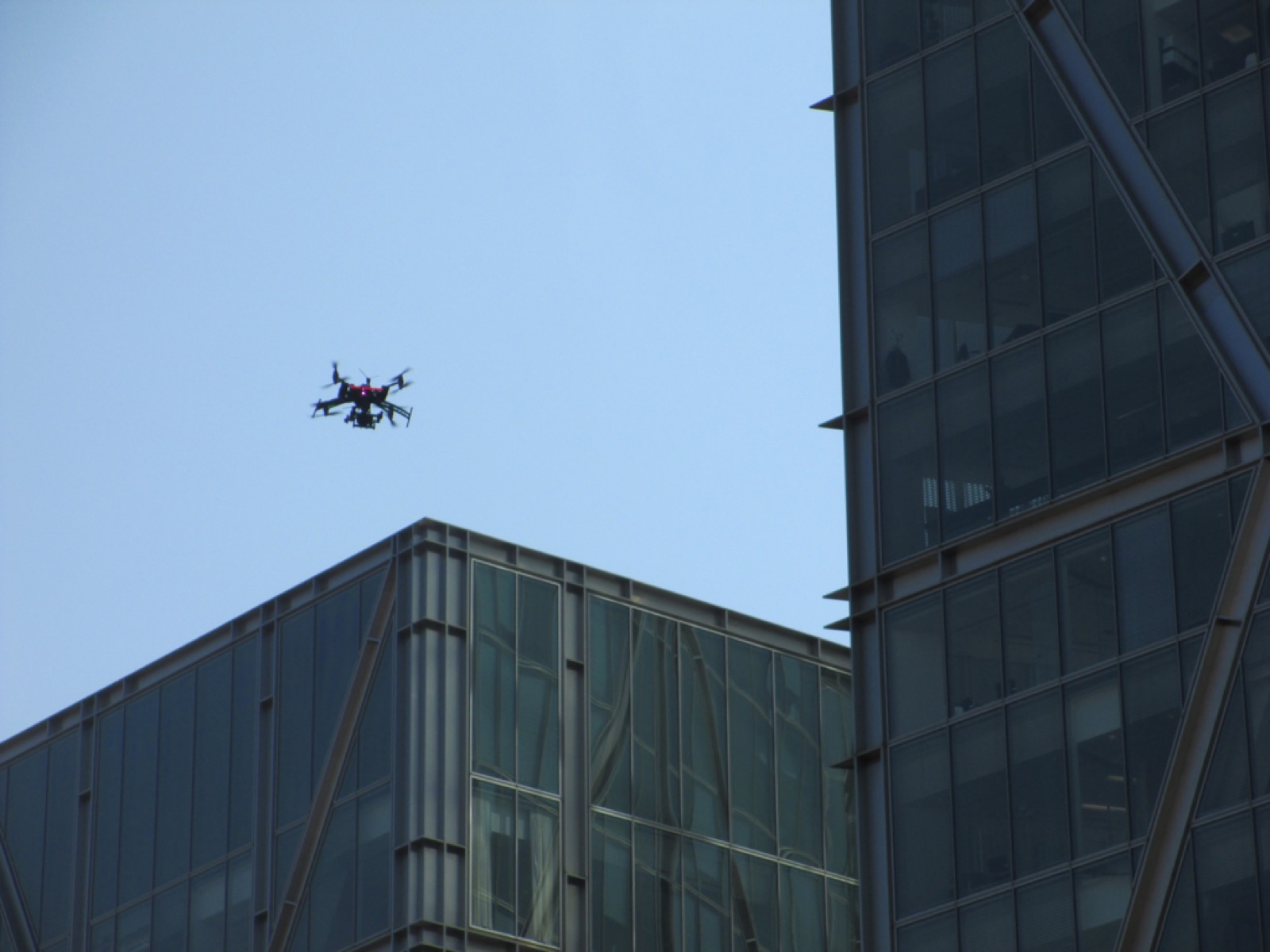 Mały dron inspekcyjny przy szklanej elewacji biurowca